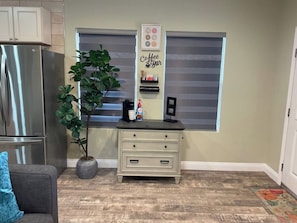 A kitchen with a stainless steel refrigerator, a potted plant, a coffee maker, and a sign that reads 'Coffee Bar'.