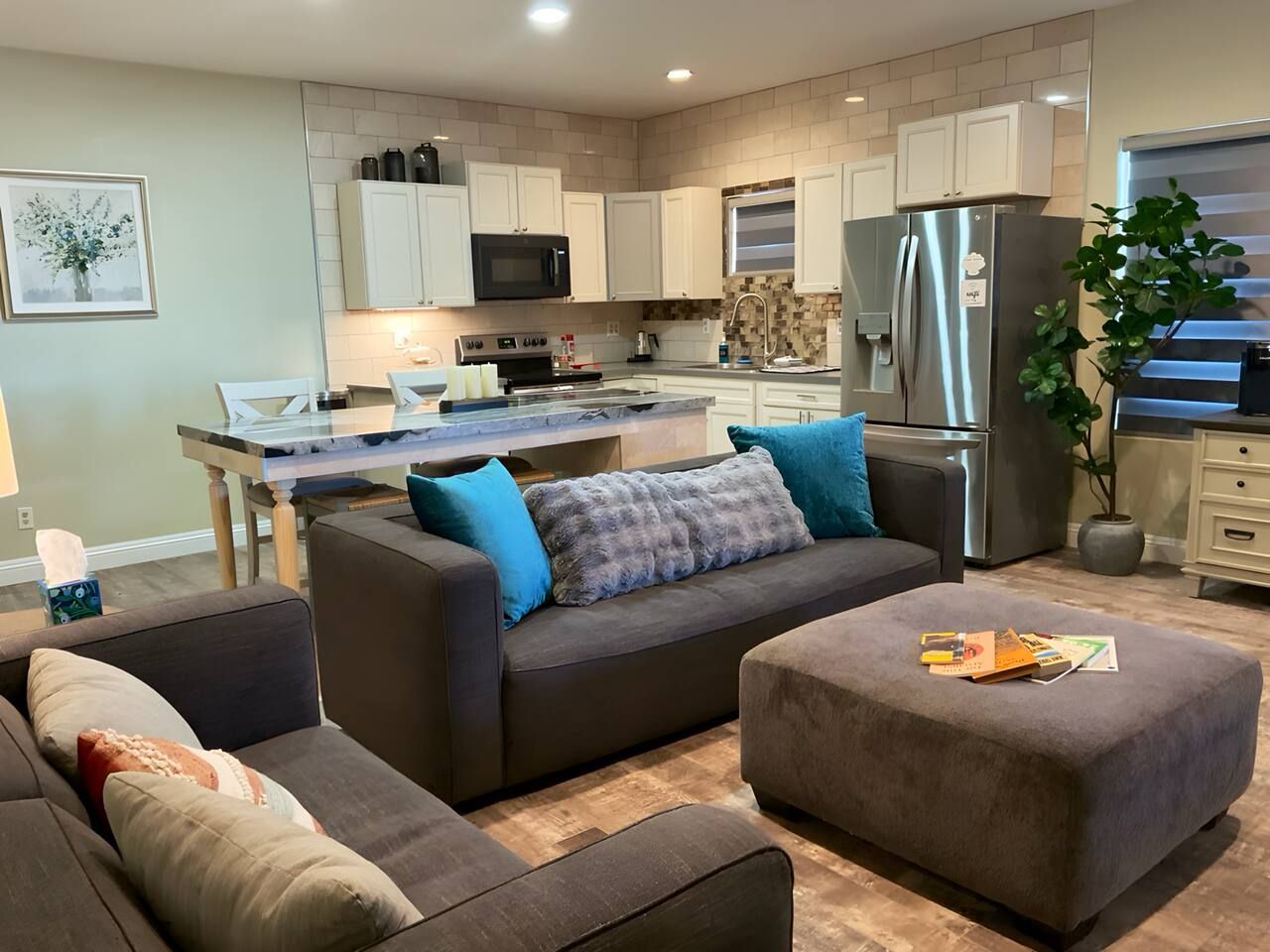 A modern living room with a sofa, ottoman, and a dining table.