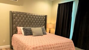 A bed with a tufted headboard, a pink patterned bedspread, and two pillows. - Updated near Death Valley, large outdoor space (Amargosa Valley)