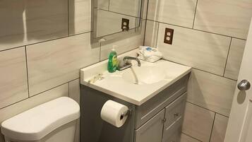 Un baño con inodoro, lavamanos, espejo y paredes con azulejos.