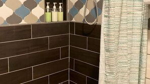 A shower area with a patterned wall, a showerhead, and a striped shower curtain. - Updated near Death Valley, large outdoor space (Amargosa Valley)