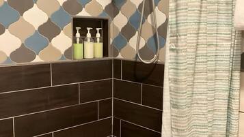 A shower area with a patterned wall, a showerhead, and a striped shower curtain.