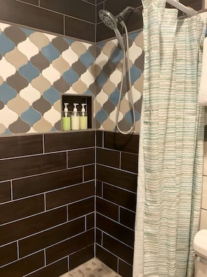 Un área de ducha con pared estampada, cabezal de ducha y cortina de baño a rayas.