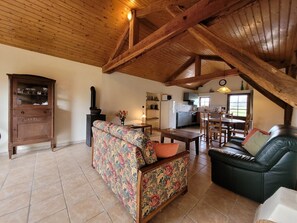 A spacious living area with a high ceiling, a fireplace, a dining table, and a sofa. - Gite With Garden and Shared Pool (Saint-Saud-Lacoussiere)