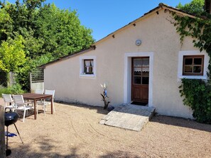 A small house with a gravel driveway, a wooden door, and a window with lace curtains. - Gite With Garden and Shared Pool (Saint-Saud-Lacoussiere)