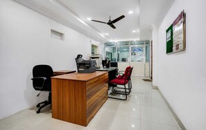 A reception area with a wooden desk, black office chairs, a ceiling fan, and a welcome sign. - Hotel O Pedagantyada Gajuwaka (Visakhapatnam)