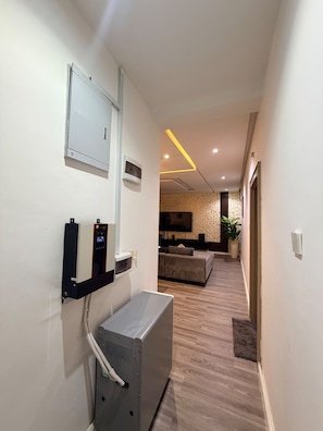 A hallway with a modern design, including a wall-mounted air conditioning unit, a flat-screen TV, and a seating area with a sofa and a coffee table. - 3 BEDROOM APARTMENT IN LIFECAMP GWARINPA ABUJA (abuja)