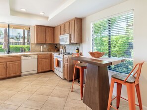 A modern kitchen with wooden cabinets, a built-in oven, a microwave, and a large window with blinds. - Modern Poolside 2 BR + Flex Space, Golf + Club Access (Palm Desert)