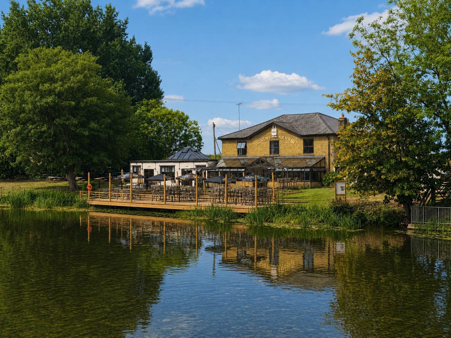 A riverside building with outdoor seating, a dock, and a clear sky.