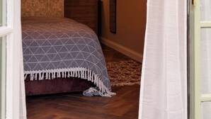 A bedroom with a patterned bedspread, a hanging lamp, a dresser, and a mirror on the wall. - the Jenyns  (Denver)