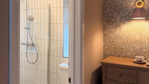 A bathroom with a shower, toilet, and a vanity with a lamp. - the Jenyns  (Denver)