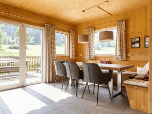 A wooden interior with a dining table, chairs, a bench, and curtains. - One-bedroom Cabin (Sankt Georgen am Kreischberg)