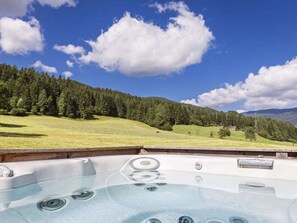 A hot tub with a clear view of a mountainous landscape and a forested area in the background. - One-bedroom Cabin (Sankt Georgen am Kreischberg)