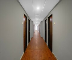 Un lungo e stretto corridoio con pavimento in legno e porte su entrambi i lati, che conduce a un'area aperta in fondo.