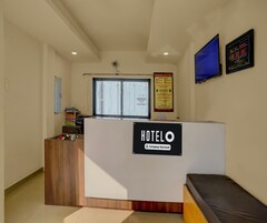 A hotel reception area with a reception desk, a digital clock, and a window with blinds.