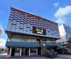 Un hotel con una facciata moderna, una segnaletica ben visibile che indica un hotel destinato a servizi aziendali, e una scala che conduce all'ingresso.