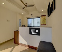 A hotel reception area with a reception desk, a ceiling fan, and a window with a view of buildings outside.