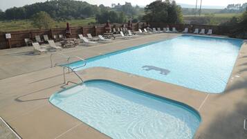 Ein rechteckiger Pool im Freien mit einer Holzterrasse und Liegestühlen.