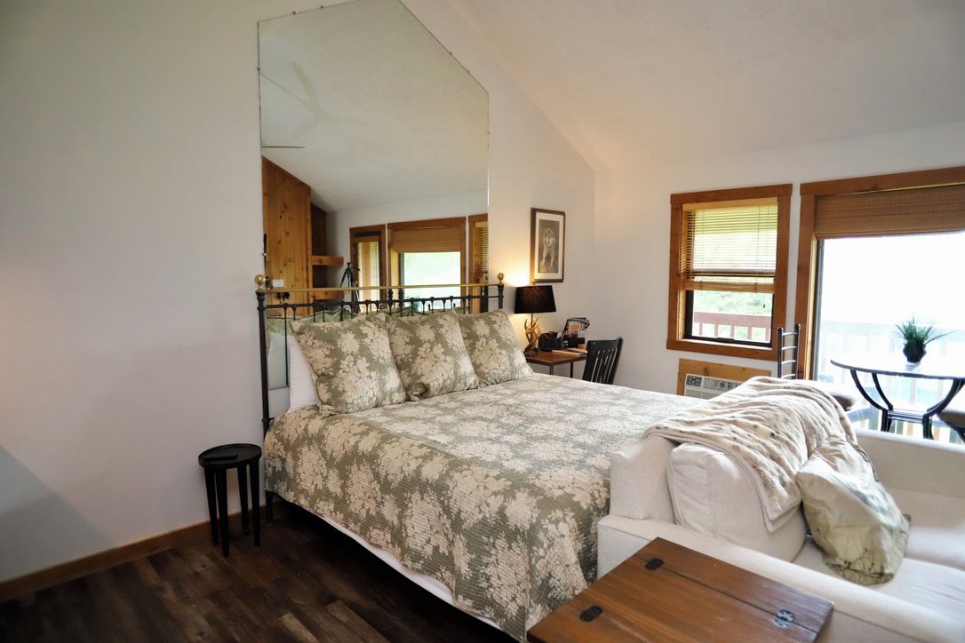 Ein Schlafzimmer mit einem Bett, einem kleinen Tisch, einer Couch und einem Fenster mit Jalousien.