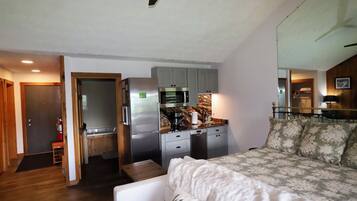 Espaço compacto com cozinha compacta, cama e pequeno espaço para sentar.