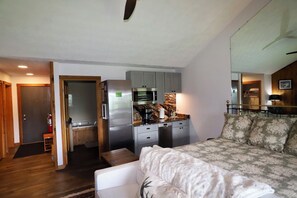 Een knus verblijf met een kitchenette, een bed en een zithoekje.