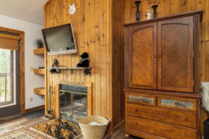 A wooden interior with a fireplace, a television mounted on the wall, and a large wooden cabinet.