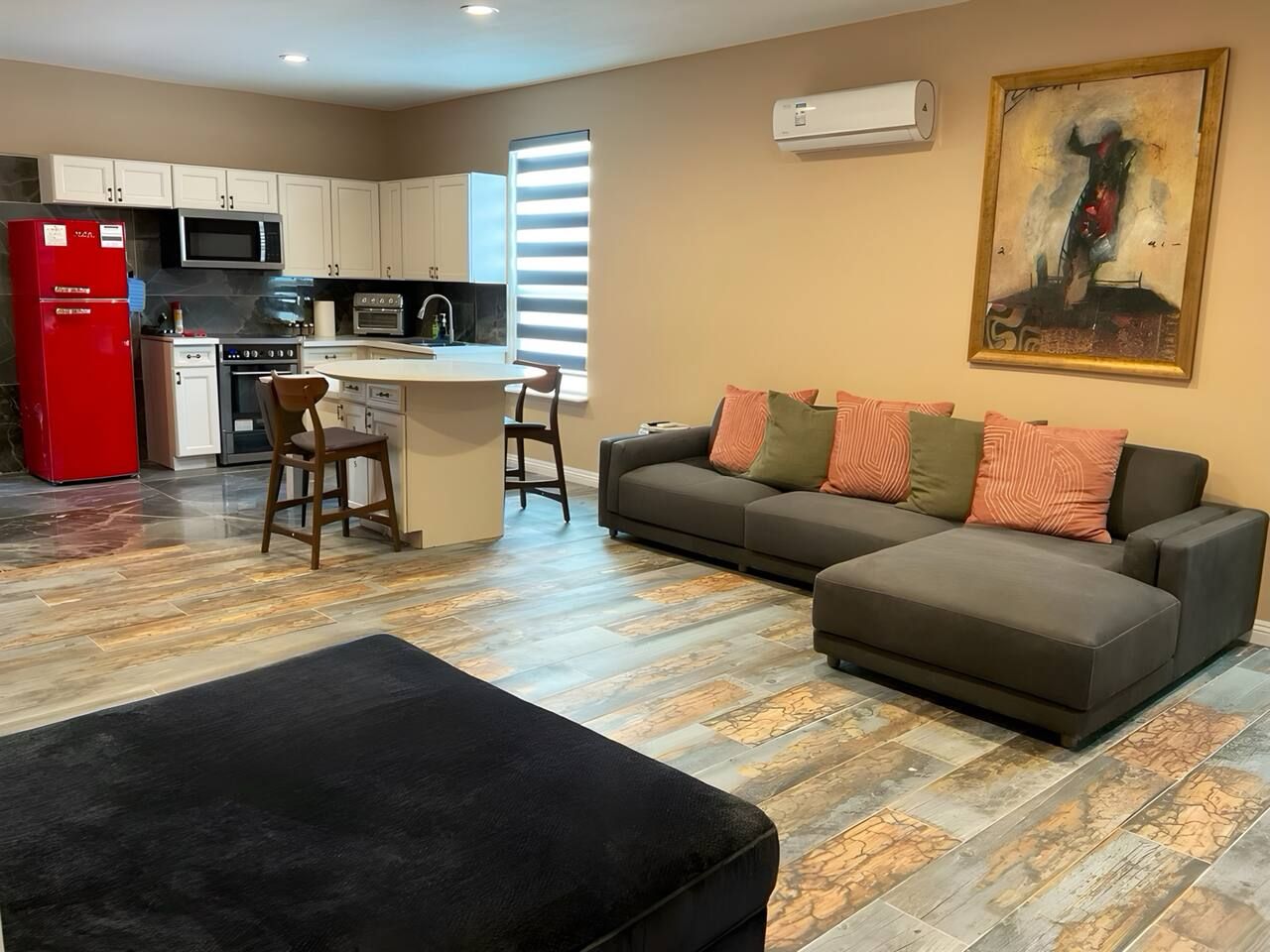 A modern living room with a sofa, ottoman, and a dining area with chairs.
