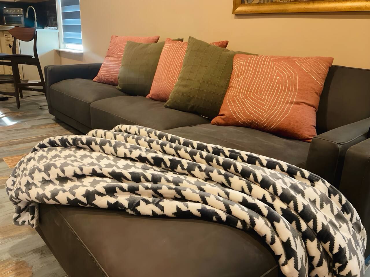 Un salon avec un canapé, plusieurs coussins et un plaid à motifs.