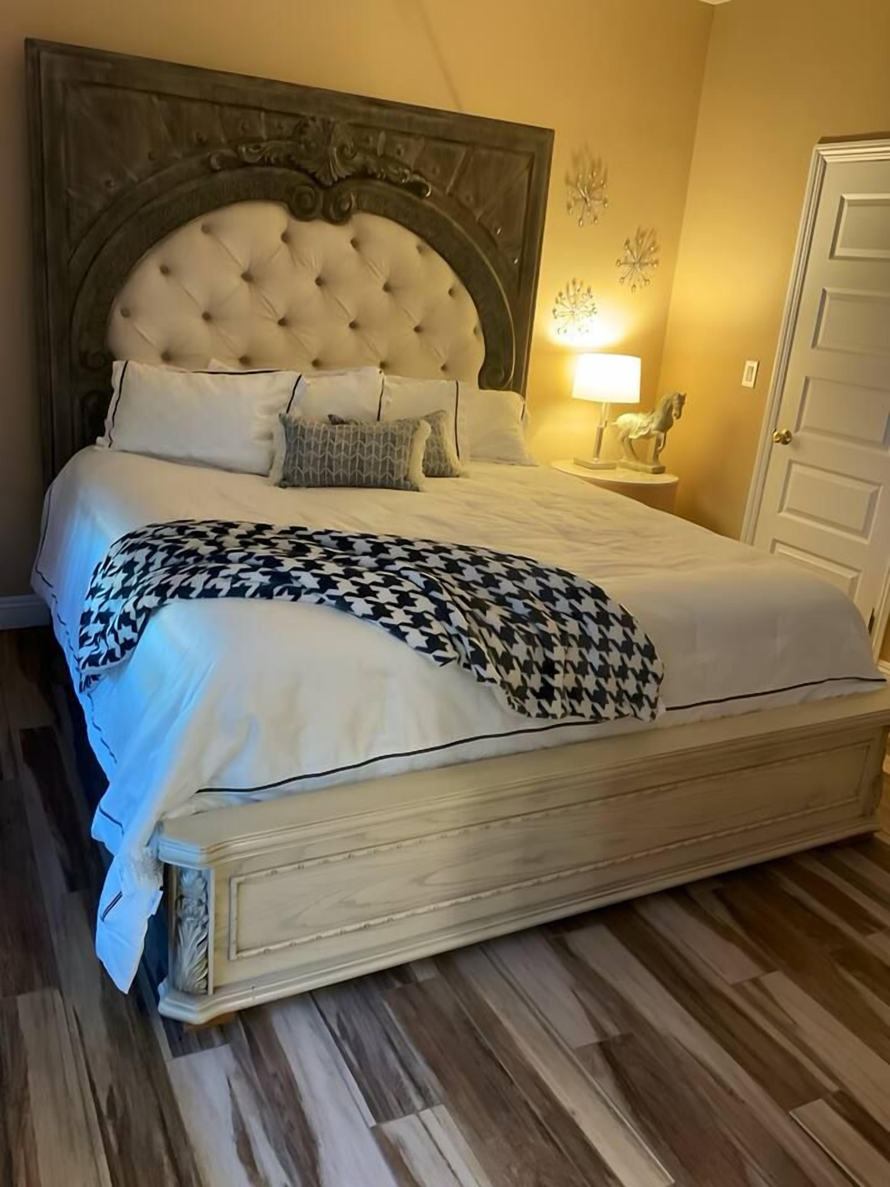 A bed with a tufted headboard, white bedding, and a houndstooth throw blanket.