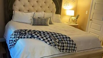 A bed with a tufted headboard, white bedding, and a houndstooth throw blanket.