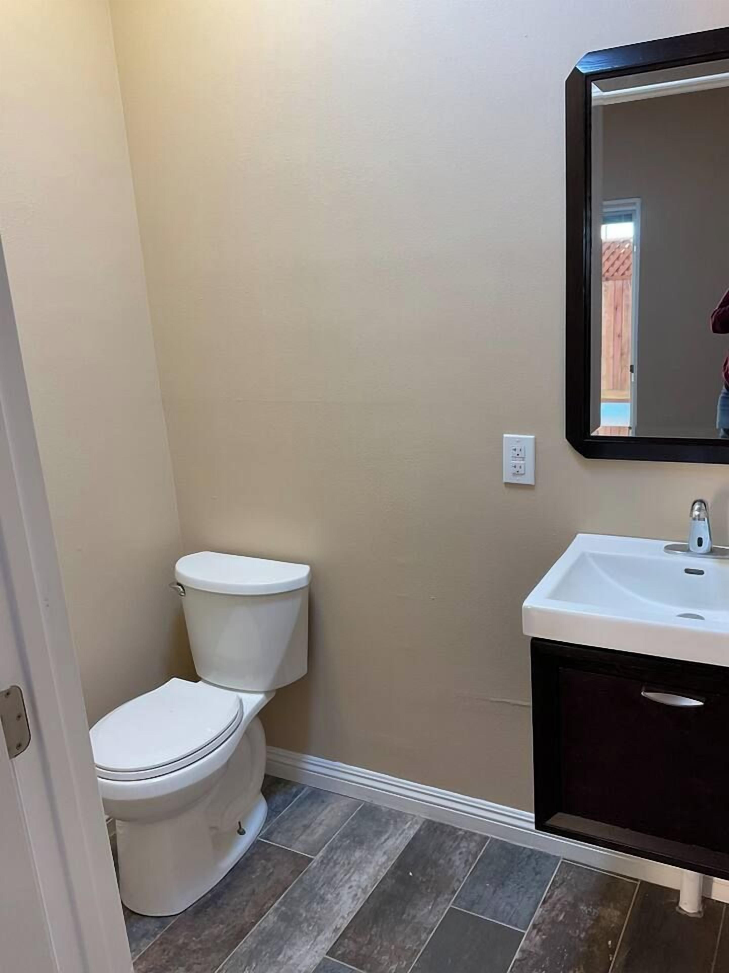 A bathroom with a toilet, sink, and mirror.