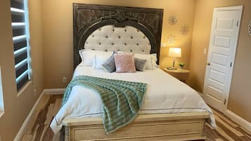 A bedroom with a large bed, a nightstand, a lamp, and a door.