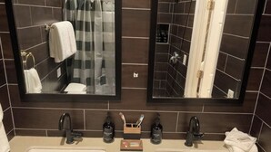 Ein Badezimmer mit zwei Waschbecken, einem Spiegel und Toilettenartikeln.