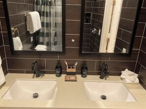 Un baño con dos lavamanos, un espejo y artículos de aseo.