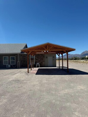 A building with a covered outdoor area, a stone facade, and a clear sky.