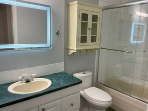 A bathroom with a glass-enclosed shower, a sink with a marble countertop, a toilet, and a cabinet above the sink. - Bright Entire Walkout Suite, Stunning Mt Baker Views (Abbotsford)