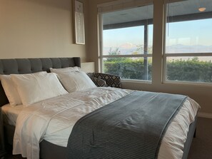 A bed with a grey headboard, white and patterned pillows, and a grey blanket. - Bright Entire Walkout Suite, Stunning Mt Baker Views (Abbotsford)