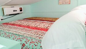 Quarto com uma cama, ar condicionado fixado na parede e uma placa com texto.