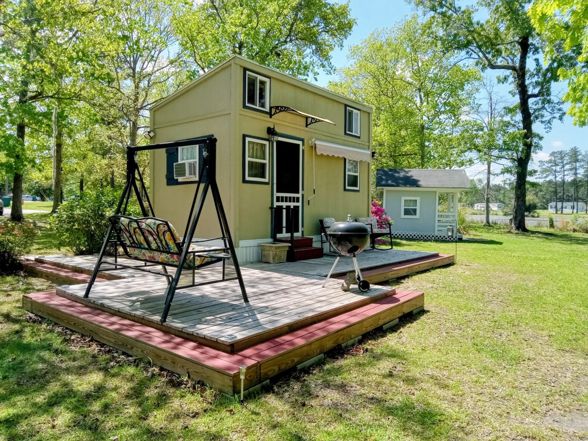 A two-story house with a porch, a swing set, and a barbecue grill.