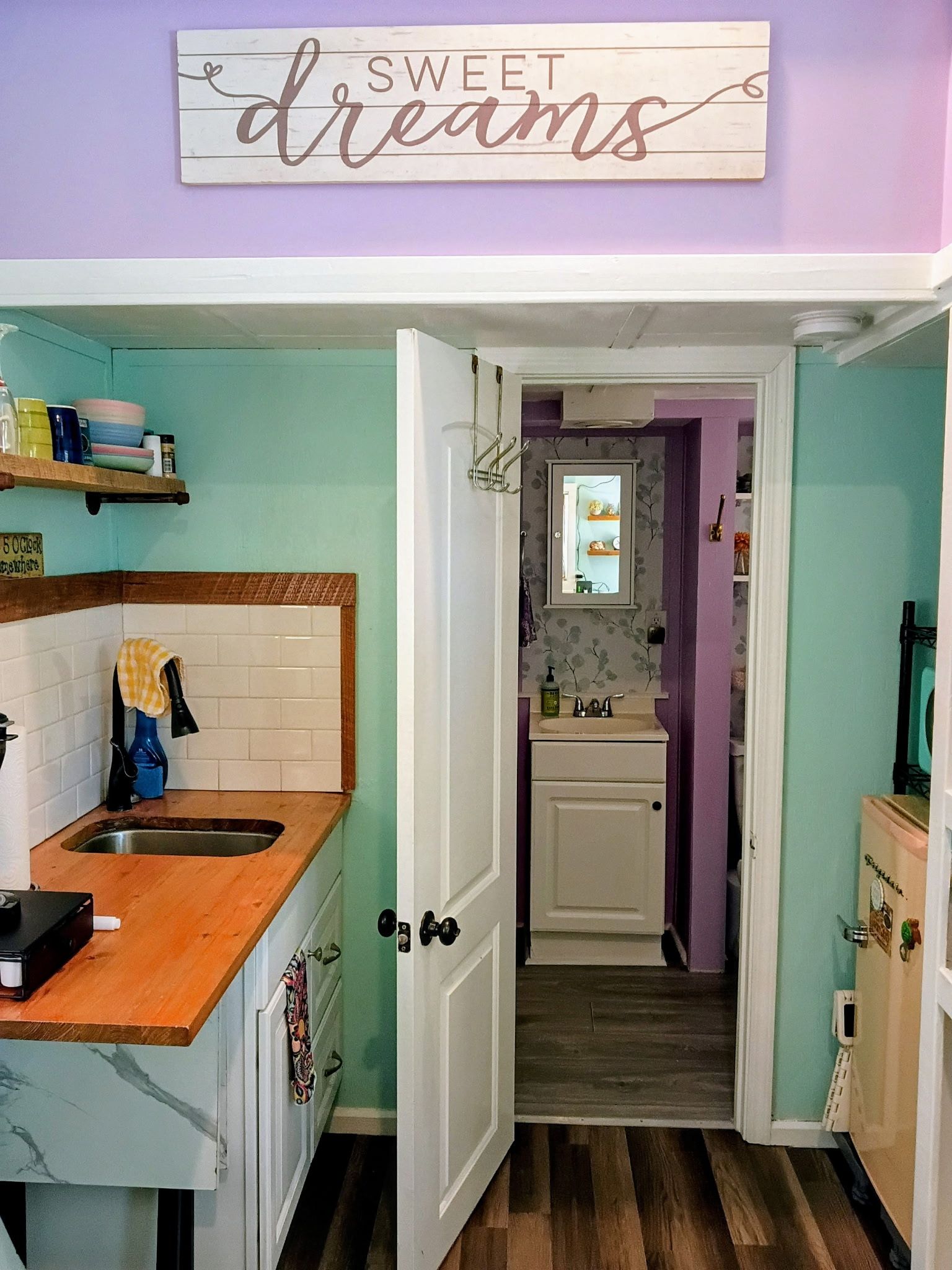 A kitchen with a wooden countertop, a sink, and a cabinet. There is a sign above the sink that reads 'SWEET dreams'.