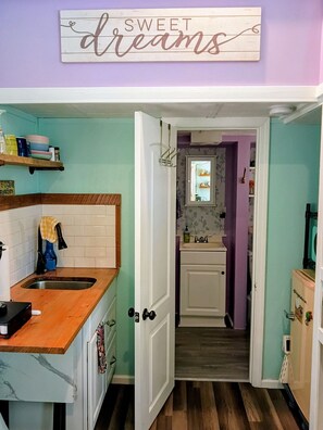Une cuisine avec un plan de travail en bois, un évier et un placard. Au-dessus de l’évier, on peut lire une inscription : « DOUX rêves ».