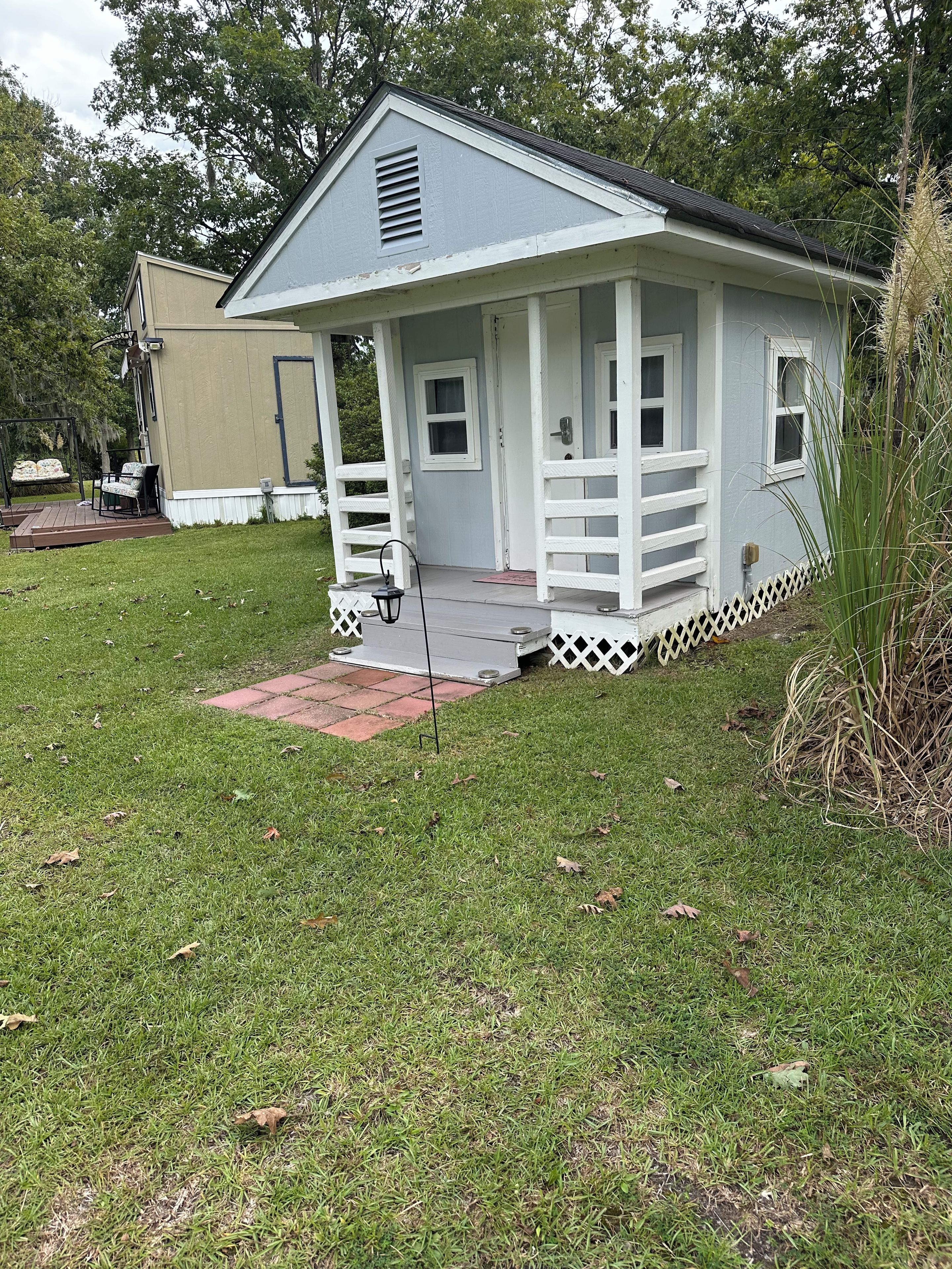 A small, single-story building with a porch and a fenced yard.