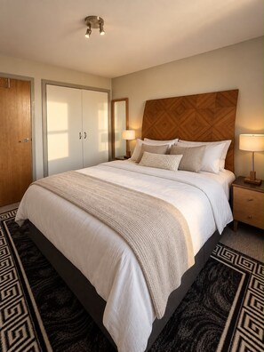 Ein Hotelzimmer mit einem großen Bett, einem Holz-Kopfteil, einem Nachttisch mit Lampe und einem Kleiderschrank.