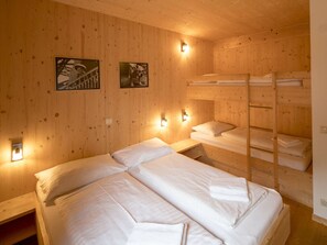 A wooden room with bunk beds, two wall-mounted lights, and two framed pictures. - Cabin With 1 Bedroom (Sankt Georgen am Kreischberg)