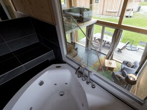 A bathroom with a large bathtub, a glass shower enclosure, and a view of an outdoor deck with furniture. - Cabin With 1 Bedroom (Sankt Georgen am Kreischberg)
