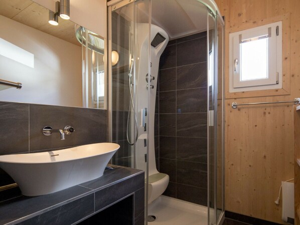 A modern bathroom with a freestanding bathtub, a glass-enclosed shower, and a wooden wall. - Cabin With 1 Bedroom (Sankt Georgen am Kreischberg)