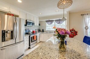 Una cocina moderna con electrodomésticos de acero inoxidable, encimera de granito y un florero con flores.