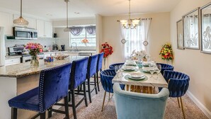 Une cuisine moderne avec des meubles blancs, un îlot central et des chaises en velours bleu.