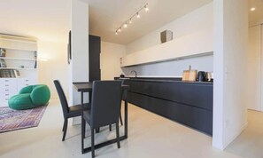 A modern kitchen with a dining area, featuring a black countertop, a dining table with chairs, and a green bean bag chair. - VASARI LUXURY – SOPHISTICATED FLORENCE HOME WITH RIVER VIEWS (Firenze)