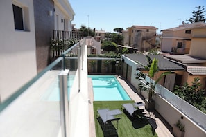 A residential area with a swimming pool, outdoor furniture, and a view of neighboring houses. - Vrbo Property (Lido Manfria)